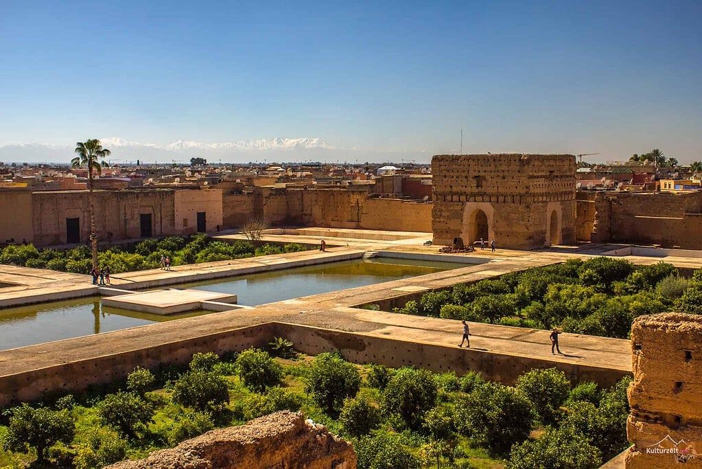 Kulturreisen Marrakesch 2027: El-Badi Palast mit Wasserbecken, Orangenhainen und Atlasgebirge im Hintergrund.