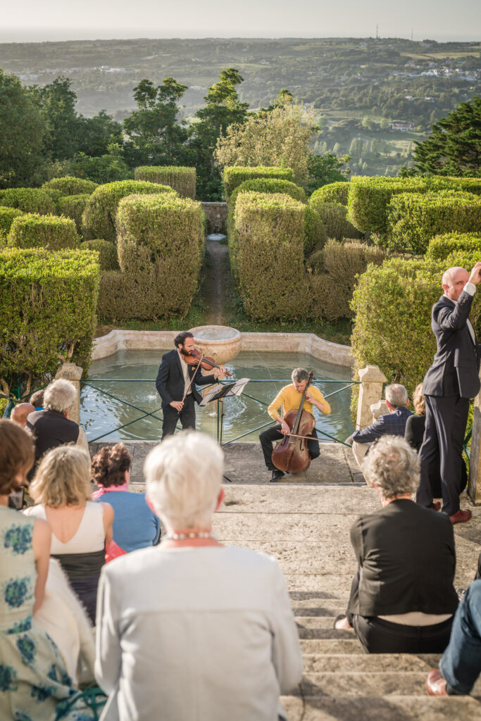 Reise Programm Sintra 2027 12 Kammerkonzert mit Violine und Cello in einem Garten von Sintra, mit Zuschauern und Blick auf die Landschaft – Kulturzelt Reisen 2027