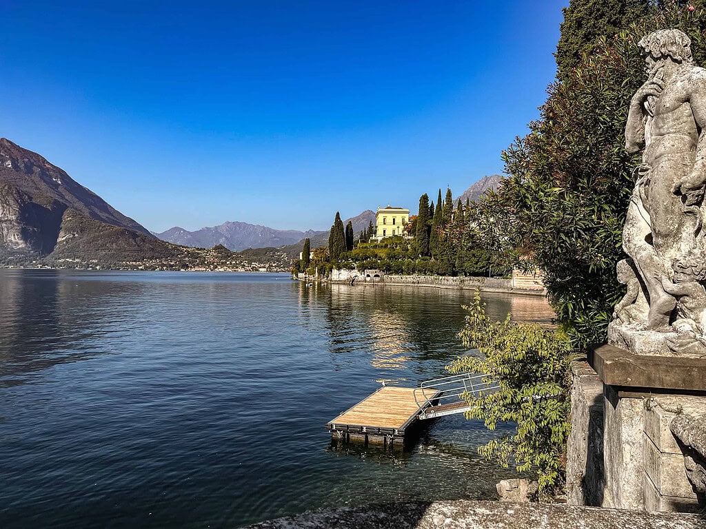 Comersee über die Reise 2026 11 Steinerne Skulptur und hölzerner Bootssteg in einem historischen Garten am Comersee, mit Blick auf das Wasser und die Berge – Kulturzelt Reisen Kultur- und Gartenreise Comersee 2027
