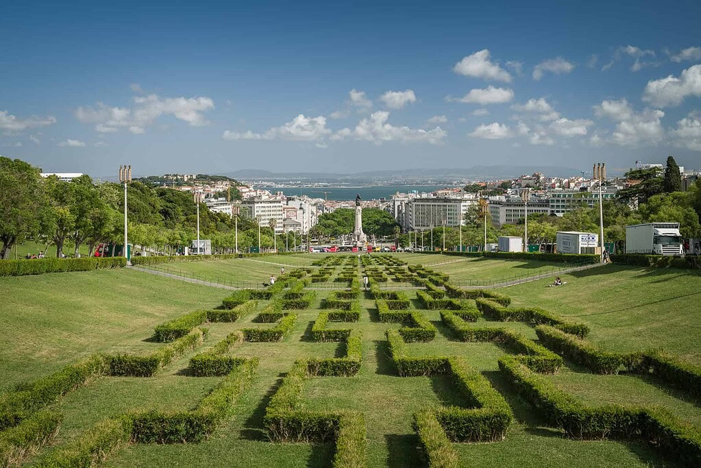KULTURZELT REISEN 17 Parterre mit geschnittenen Buchshecken im Parque Eduardo VII, dahinter die Statue des Marquês de Pombal und der Tejo